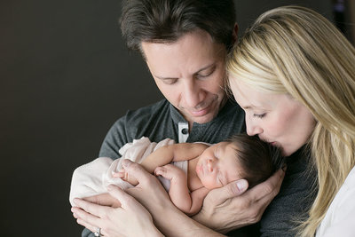 Parents of newborn baby cradling him in Denver portrait studio