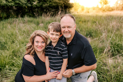 A St. Louis family of three posing for thier family portraits in a field.