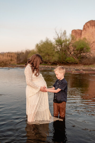 mom lets her son stand with her in the Salt River and snuggle her baby bump