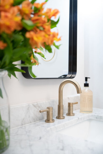 a bathroom sink with white marble countertops and a gold faucet