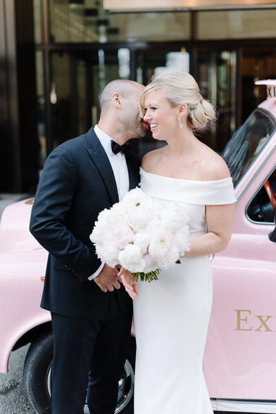 Bride and groom in front of pink car.