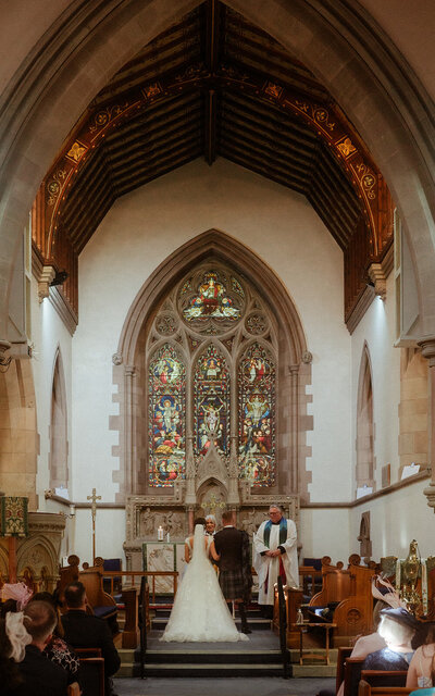 Wedding ceremony held in a beautiful church in Kelso, Scotland, capturing the sacred and emotional exchange of vows in a historic, serene setting
