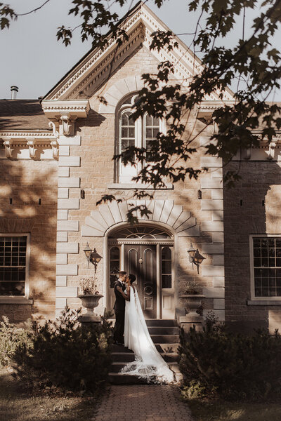 Bride and groom at building entrance, shot with natural light.