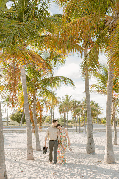 Man leads his future bride in the sand of a beach during engagement session