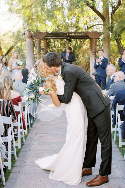 Bride and groom sharing a kiss in the aisle at their southern california wedding