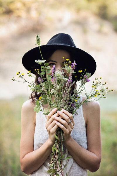 Young woman holding a bouquet of flowers in front of her face.