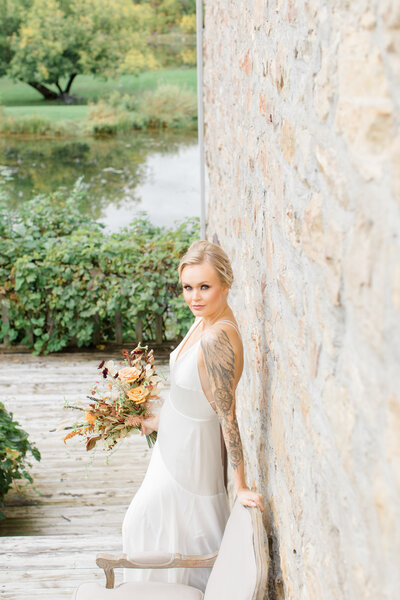 Grey Loft Studio - Bethany and Luc Barette - Wedding Photography Wedding Videography Ottawa - Modern and Ethereal Wedding at Au Vieux Moulin - Edge Tattooed bride against brick wall by the water