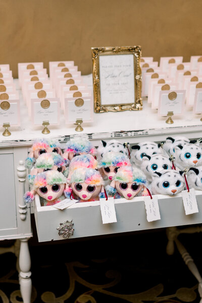 Escort card table at a 50th anniversary celebration featuring blush-colored escort cards adorned with gold wax seals. Beanie Babies are also placed on the table for children, adding a charming and personalized touch to the event at The Northern Hotel in Billings, MT