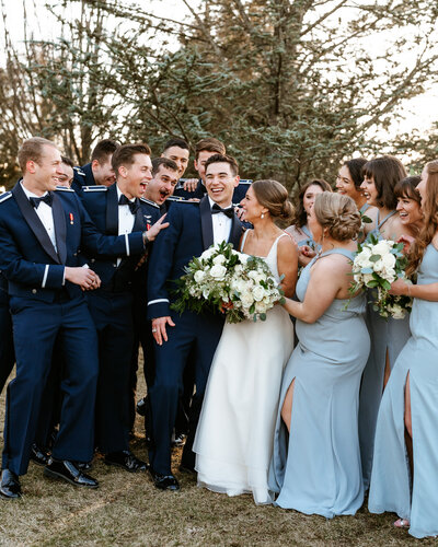 bride and groom surrounded by their bridal party  while laughing