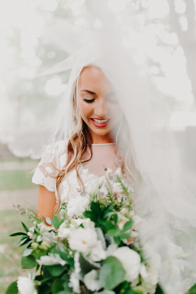 bride looking at flowers under her veil