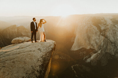 man and woman holding hands and looking over the mountain cliff