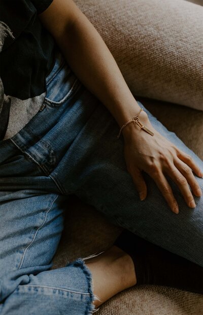 Woman sitting in jeans displaying her high-quality, eco-friendly jewelry for conscious consumers
