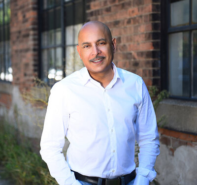 Professional outdoor headshot of a real estate agent with a red brick building in Toronto