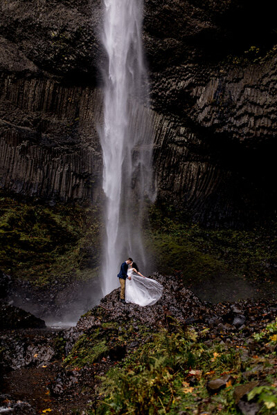 bride and groom kissing under waterfall