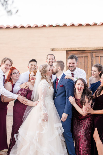Bridal party celebrating a kissing bride and groom