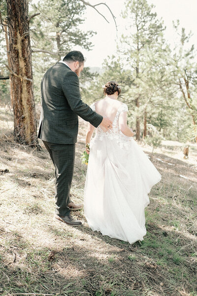 bride & groom walk together through the woods in Colorado on wedding day
