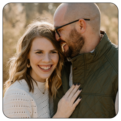 Fall photoshoot of smiling couple dressed in earth tones and smiling.