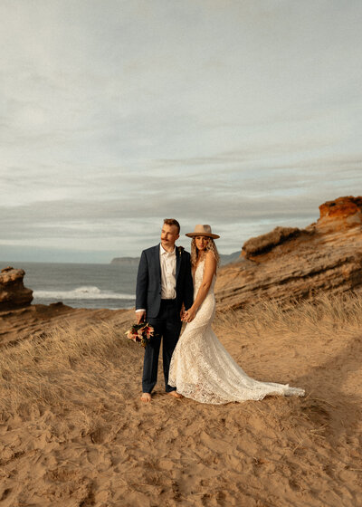 bride and groom posing on top of a sand hill in south padre island