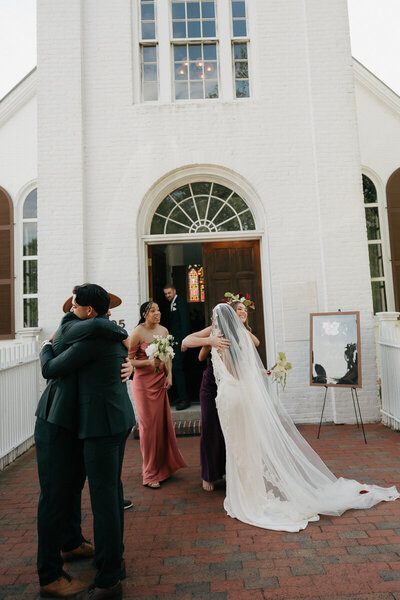 bride and groom outside church hugging their guests after the wedding ceremony
