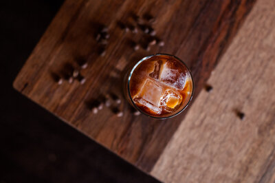 Iced Coffee on a dark wood table with coffee beans scattered