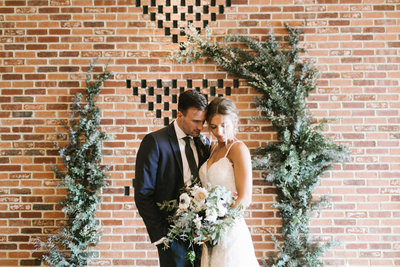Bride and groom with brick wall
