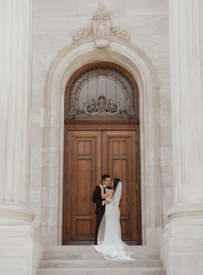 Bride and groom embracing at an ornate doorway.