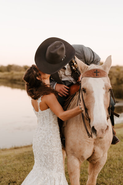 Western bride and groom kissing on horse