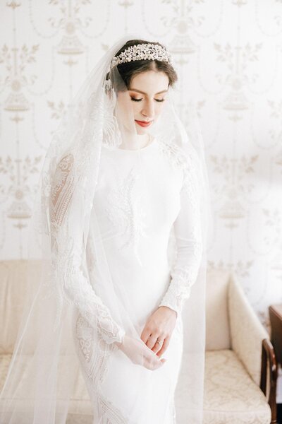 A bride in a white gown and veil posing gracefully against a patterned backdrop, captured by a Luxury Wedding Photographer.