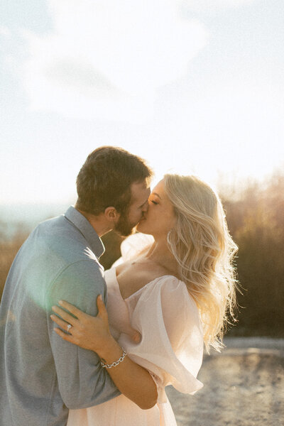 mountaintop engagement session bride and groom kissing