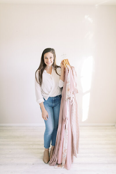 photo of madison wi family photographer Talia Laird Photography holding a bunch of beautiful flowing dresses from her client wardrobe