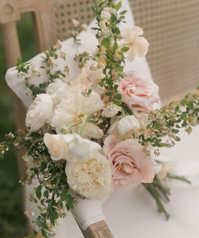 stunning pink and white rose bouquet sitting on a bench. edited with a fine art touch from a high end luxury wedding.