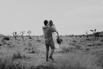 black and white image couple embracing in desert