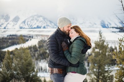 Adventurous couple cuddles in the snow of Grand Teton National Park in Wyoming