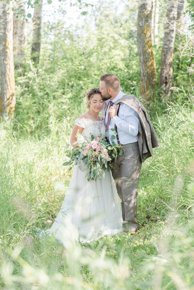 wedding photo of couple surrounded by a tall grass and trees
