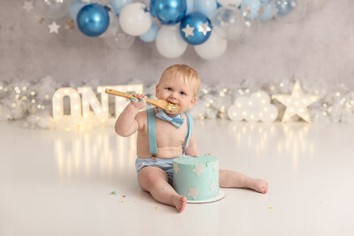 baby in blue suspenders eating cake by Philadelphia Newborn Photographer