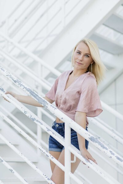 senior girl posing along white stair railing