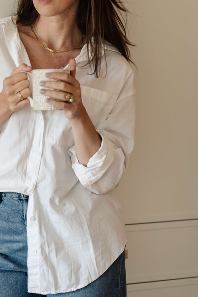 Vrouw in witte blouse die koffie drinkt na het bouwen van Showit Websites