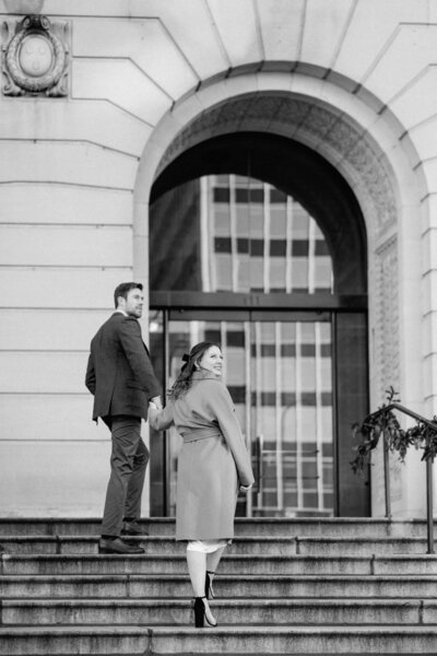 Chicago engagement photographer, Ashley Biess, captures a black and white photo of a couple walking up the steps to the Art Institute on Michigan Avenue