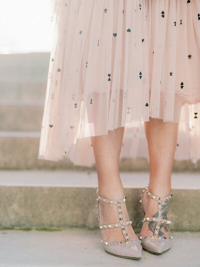 valentino studded heels in some steps with sunlight shining behind a pale pink skirt