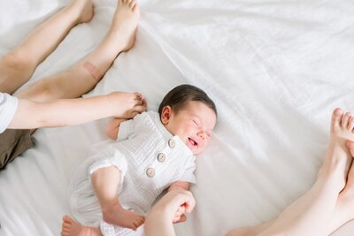 laughing newborn baby holding brothers hands in westchester