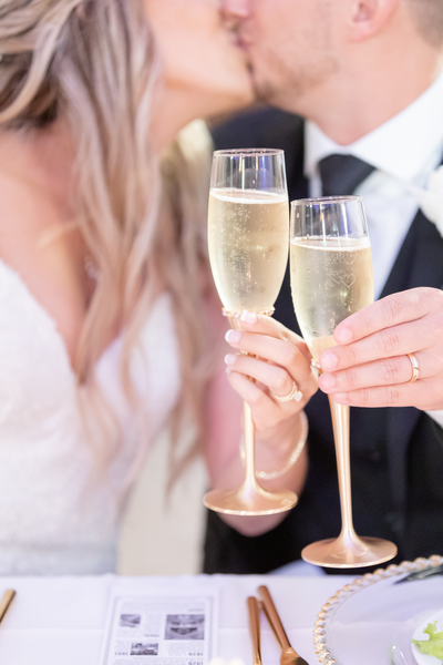 A couple holding champagne flutes and toasting while kissing