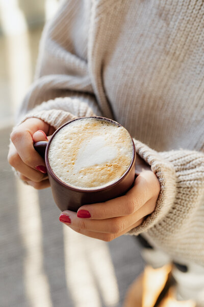Frau hält eine Tasse Kaffee in ihren Händen.