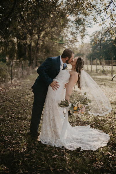 Bride and groom stop for a kiss in a field during their Northwest Arkansas Wedding
