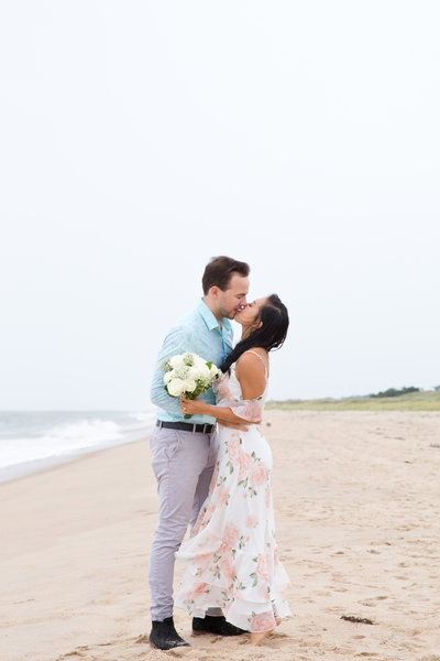Couple kiss on the beach in the rain in the Hamptons after their beach elopement.