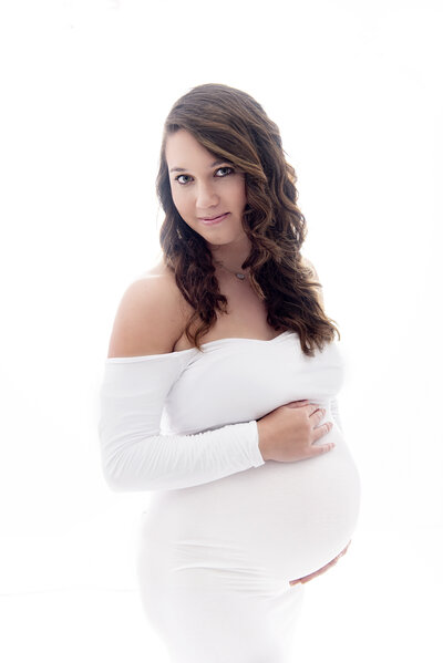 A happy mother to be in a white glamorous off the shoulder maternity gown