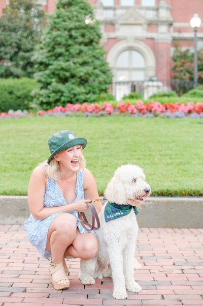 Nursing school grad smiles with her dog on Johns Hopkins Medical Campus during grad session photographed by Cait Kramer Photography