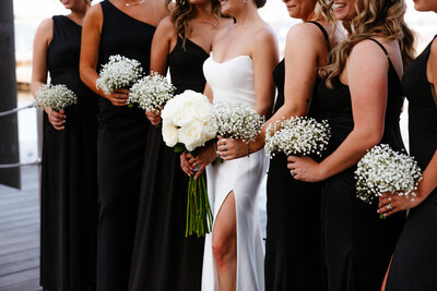 bride and bridesmaids standing all together holding their flower bouquets