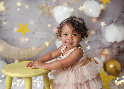 Cutie posing in front of the moon and starts at her denver  cake smash photography session.