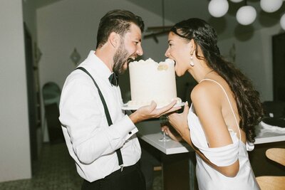 Bride and groom biting into wedding cake