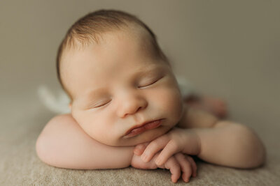 Peaceful slumber of a newborn baby resting with a serene expression, captured by a Harrisburg Newborn Photographer during a studio newborn session.